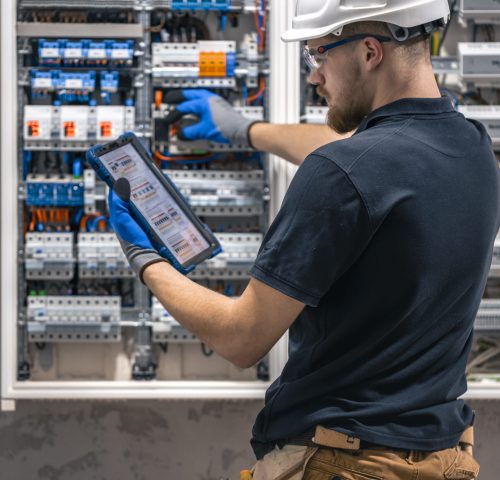 Electrical technician working in a switchboard with fuses, uses a tablet. Electrical technician looking focused while working in a switchboard with fuses. SSUCv3H4sIAAAAAAAACpySwW6DMAyG75P2DijnIgGBju5Vqh1MSMFqmlRJ6DRVffc5CaDsOnHBn+3f/jHP97eiYAM4FOyzeIaIYlRqcd6CR6MJV4eVW6lHaXPysPxY5QAwj+SI3lgElcMBvJg13CRBvSgV8CsmmfPgFydd2GVFArycSCPBXSItfE5xsSVikjooxdghY24ZIttQEv9XZ3r52g1PUoufuHBmxEolIRk5p1J2/fbS3nJrsIxoMlcPI0CFAp4pAd7Bwp++u0WBesqI8XO8y6YkzKK9DVvtZpgy5g6DCl/9QmPkxmdwjsrHjWezBf0F5pbN0cZHT6sqG+k4Iaw5747NBz193fZN1ZzWgnTQGUknrrMJUSyuOOauMGxAJzi1XVdBCU3Ly7aq67Lvu65seNe3cOLHgV/oFq9fAAAA//8DAIlQOhS5AgAA